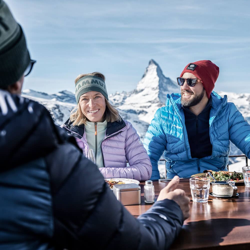 Friends enjoying alpine lunch with Matterhorn view in Zermatt mountains