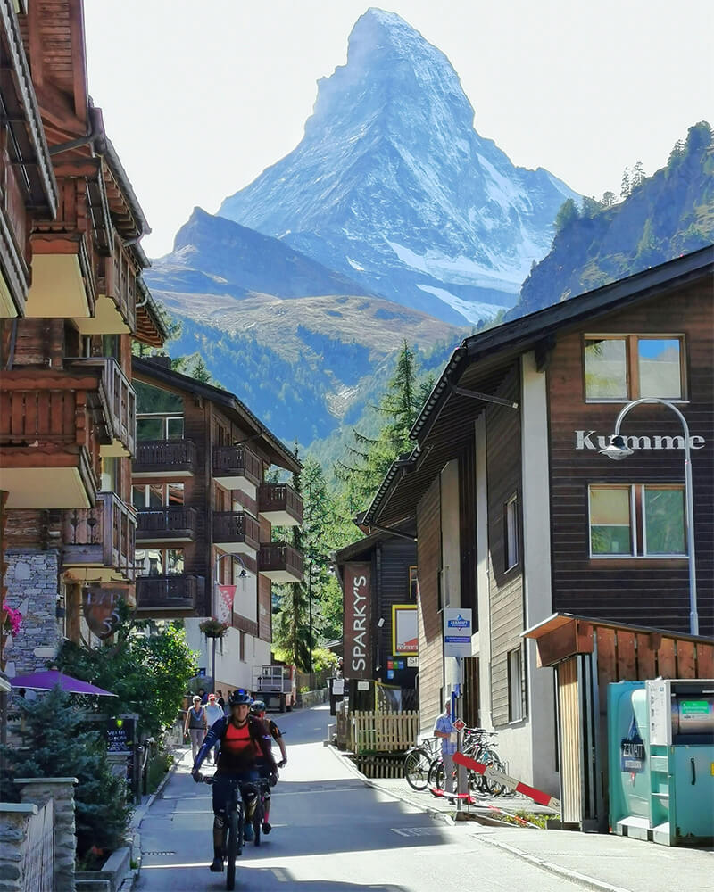 Scenic street in Zermatt with Matterhorn view and cyclists exploring car-free village