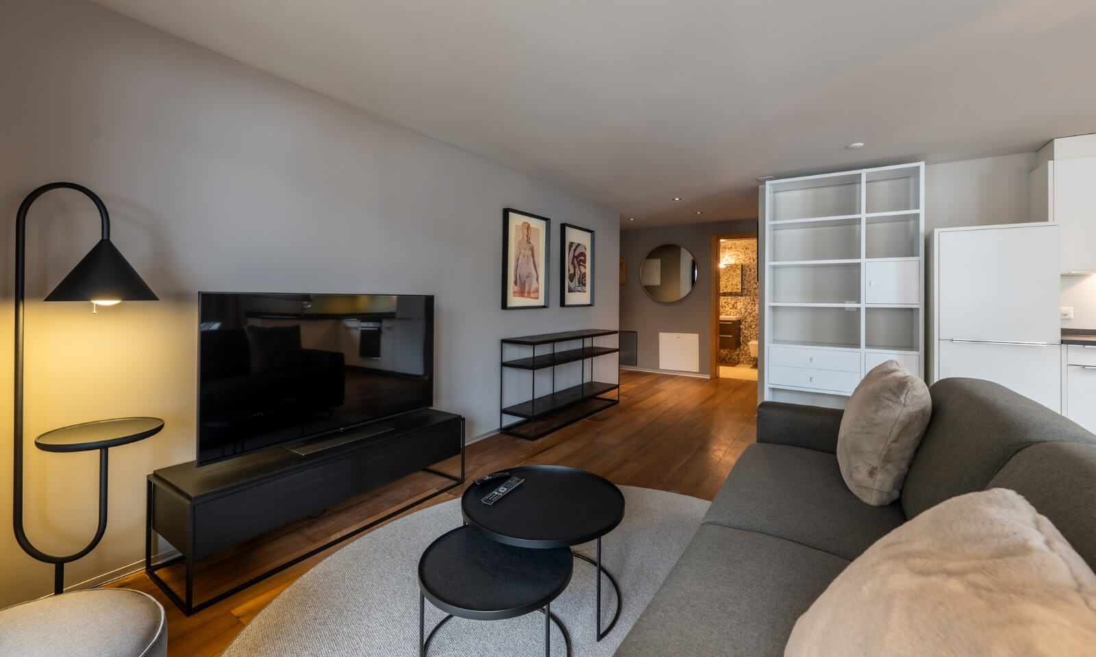 Spacious living room with sofa, artwork and open view into hallway and bathroom