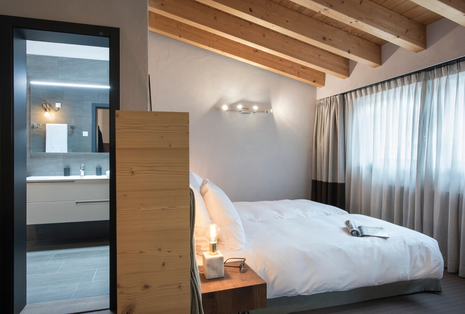 Bright Zermatt holiday bedroom with ensuite bathroom and wooden alpine ceiling