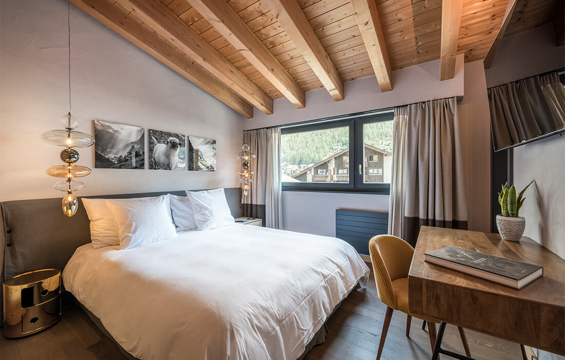 Comfortable Zermatt vacation rental bedroom with wooden beams and mountain scenery