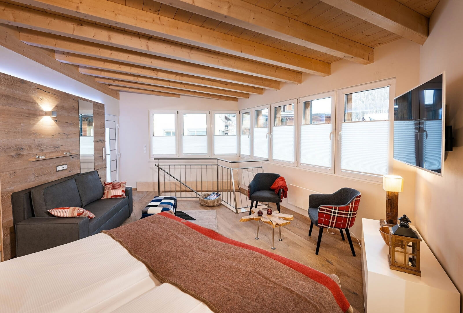 Spacious Zermatt Modern Loft with panoramic windows, cozy seating, and stylish wooden ceiling
