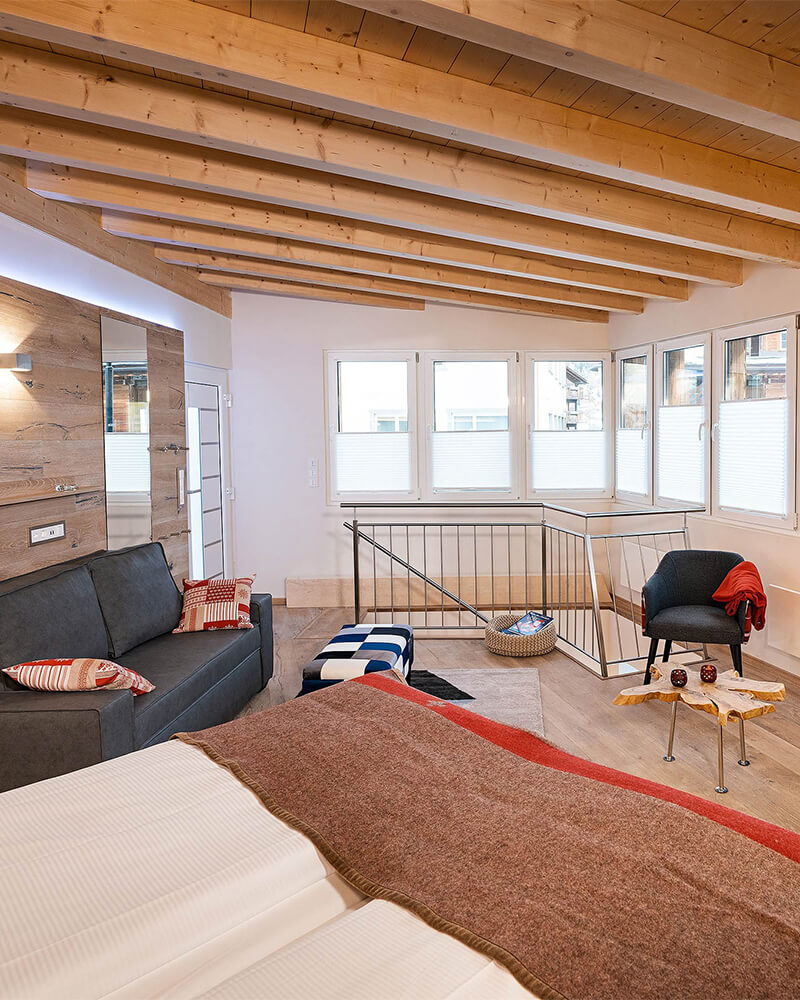 Bright Zermatt duplex bedroom with wooden ceiling, sofa and panoramic windows