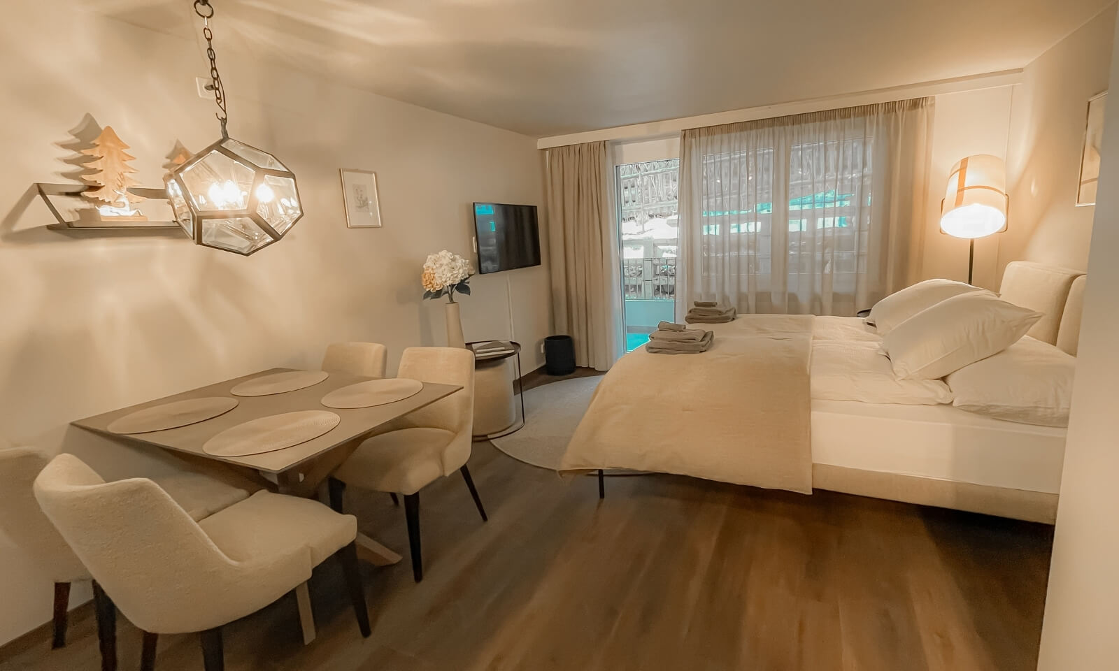 Studio JaMi Zermatt interior with dining table, double bed and balcony access.