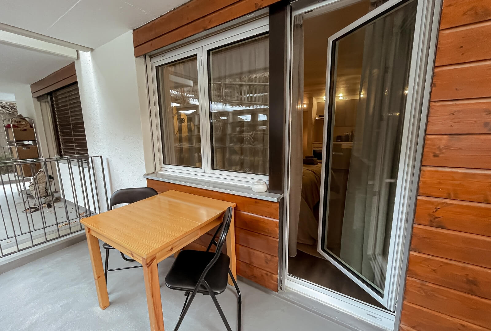 Cozy balcony at Studio JaMi Zermatt with wooden facade and seating for two.
