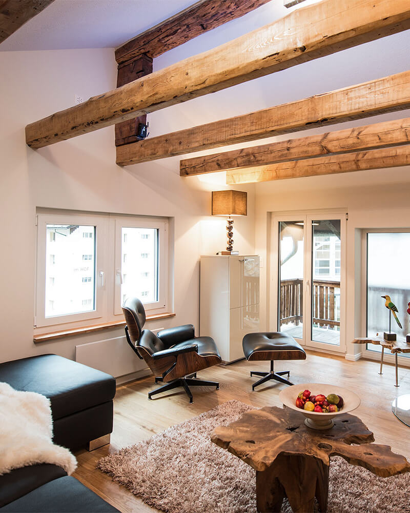 Alpine loft in Zermatt with exposed beams, modern lounge chair and cozy design