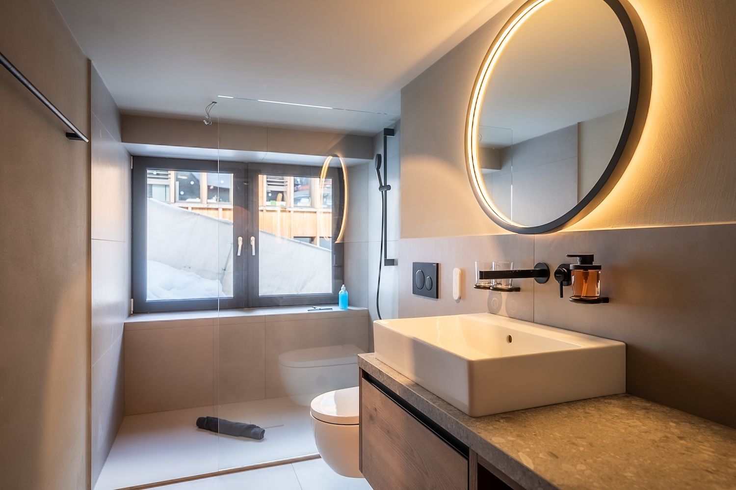 Elegant bathroom with illuminated round mirror and modern fittings at the "Zermatt Stays" residence